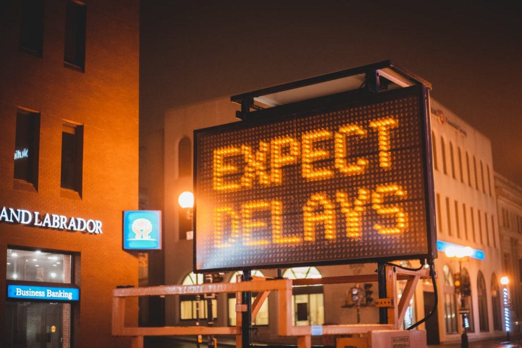 Demo Post 2 Mobile electronic traffic sign with inscription Expect delays placed on road in city street in evening time